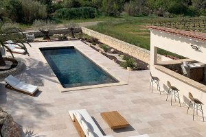 Terrasse mit Pool verkleidet mit der Kollektion Tiber, Travertin-Optik